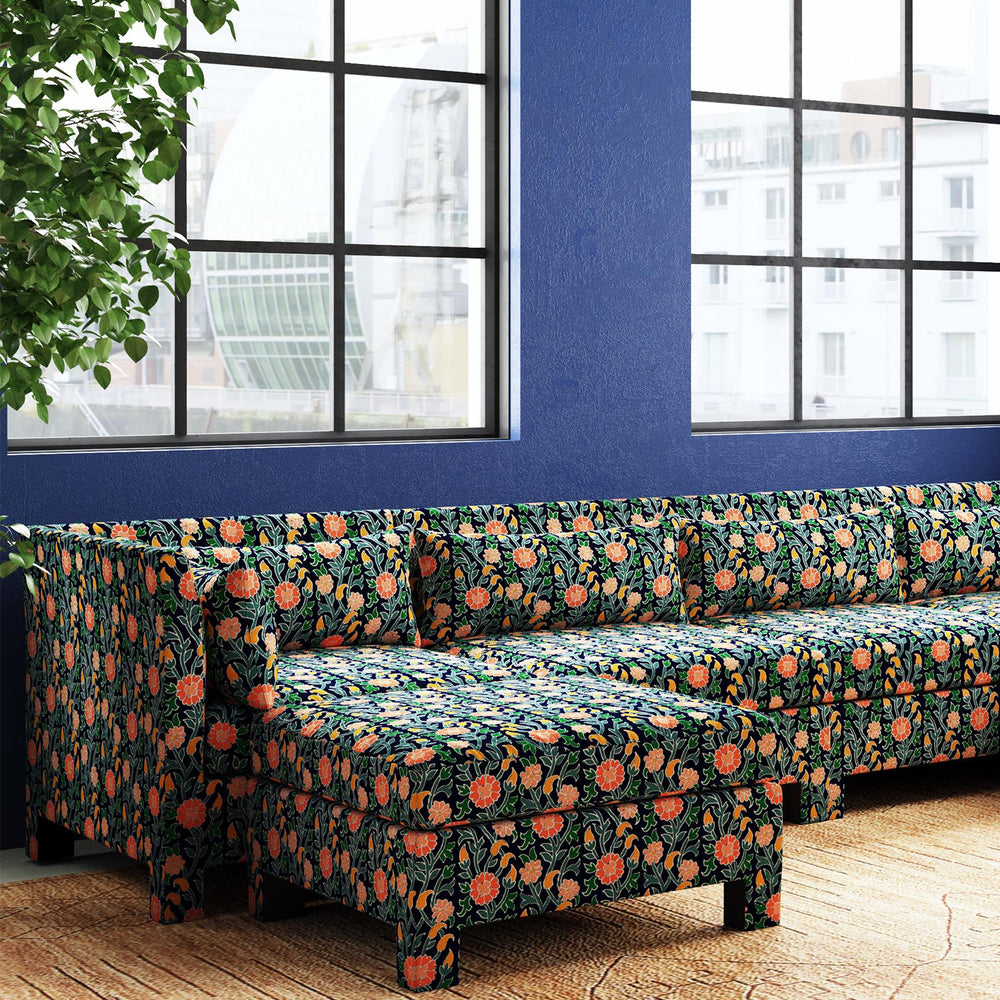 A John Robshaw Sameera Ottoman seating arrangement of a sectional sofa in a room with blue walls and a window.