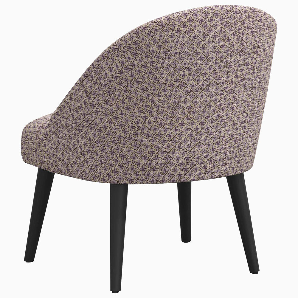 A Chetna Accent Chair by John Robshaw, upholstered in purple with black legs, featuring prints inspired by John in a mid-century silhouette.