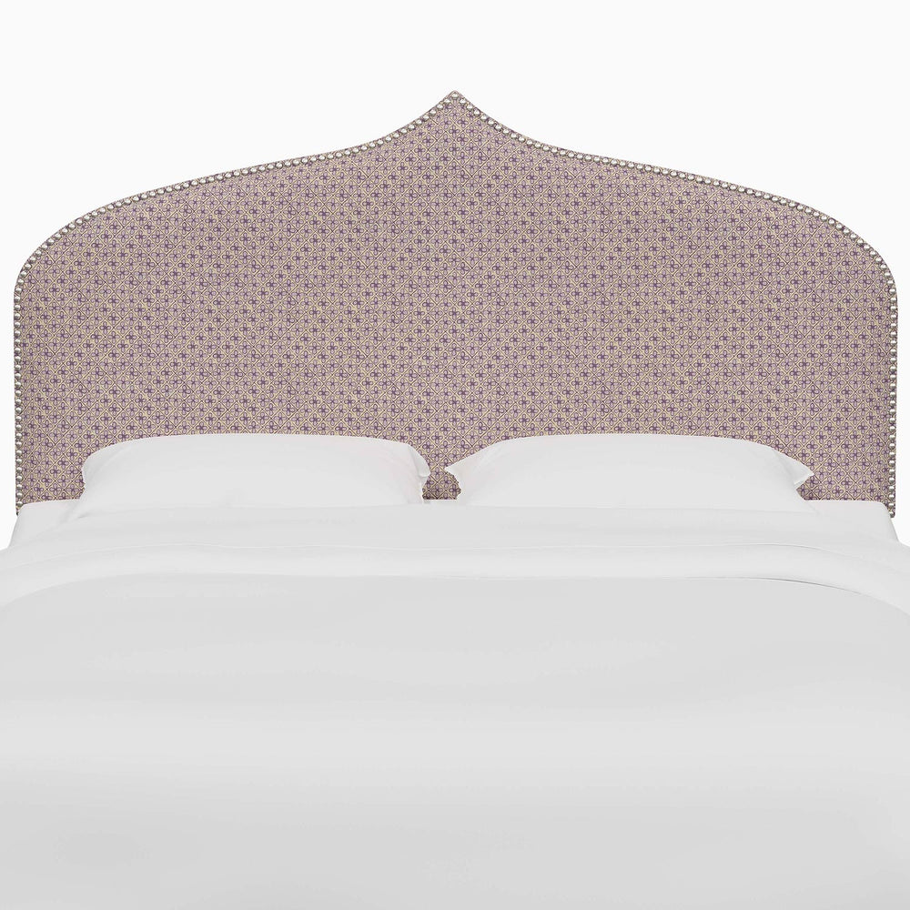 A bed with a purple John Robshaw Alina headboard and white sheets.