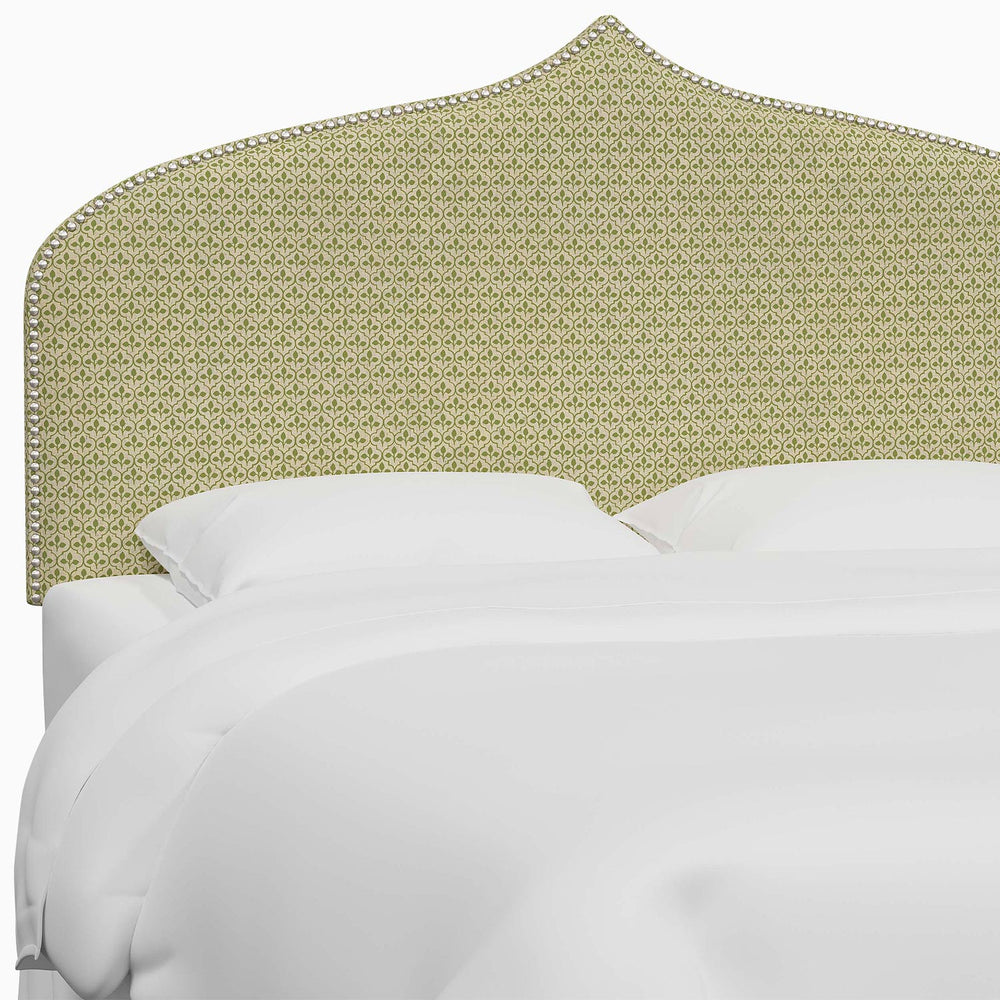A bed with a green upholstered Alina Headboard featuring Mughal arches by John Robshaw.