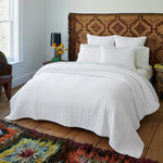 A Vivada White Woven Quilt by John Robshaw in a bedroom with a colorful cotton chambray quilt. - 29300214005806