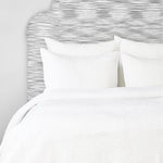 A John Robshaw Organic Hand Stitched White Quilt with organic cotton pillows and a hand-stitched headboard. - 28271560818734