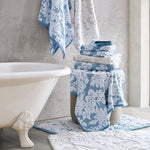 A blue and white bathroom with Pasak Blue Bath Rug from John Robshaw, bath towels, and a tub. - 28268379209774