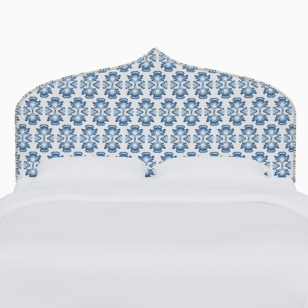 A bed with a John Robshaw Alina Headboard featuring blue and white damask prints.