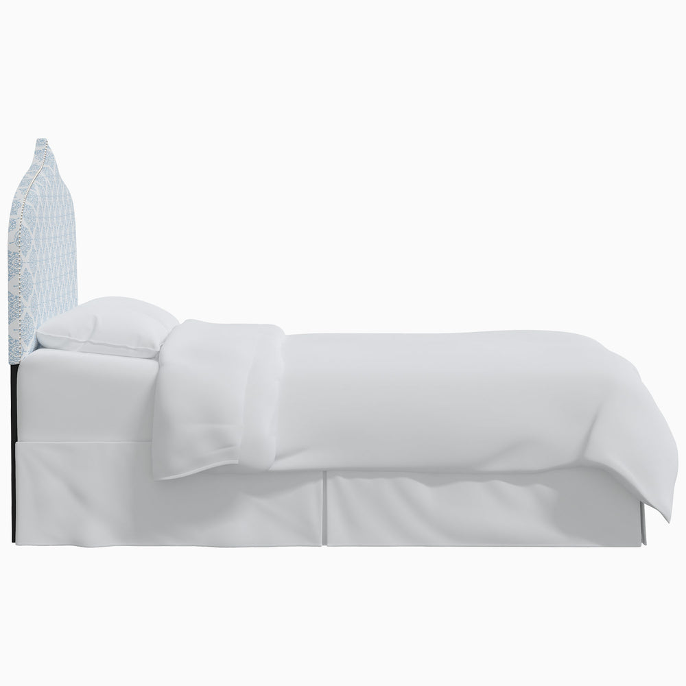 A white bed with a blue John Robshaw Alina headboard.