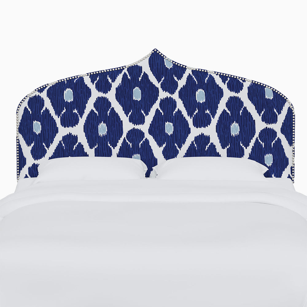 A bed with a blue and white John Robshaw Alina Headboard.