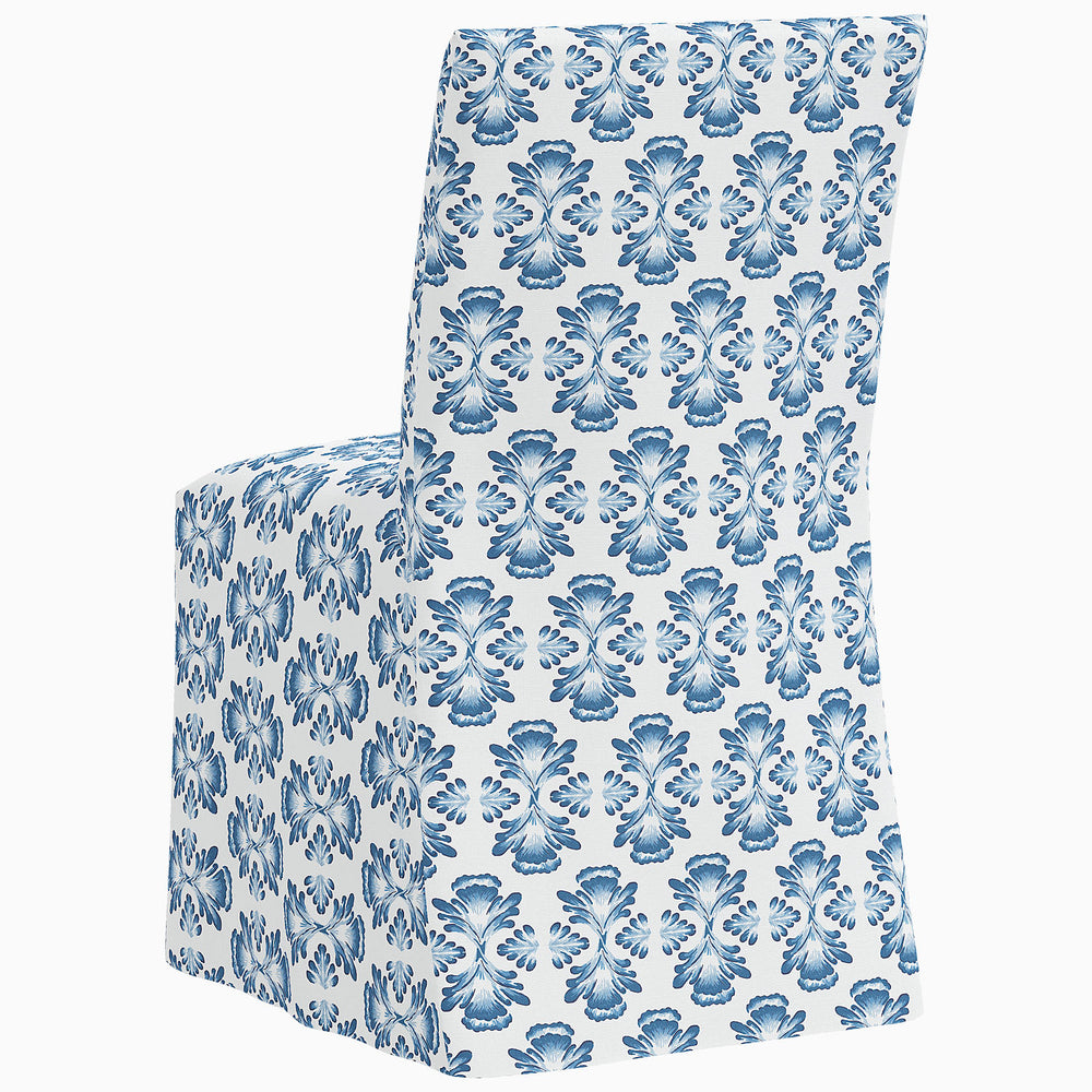 The John Robshaw Sadia Slipcover Chair is a blue and white dining chair with a floral pattern.