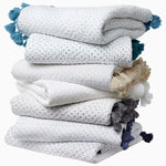 A stack of white and blue Sahati Charcoal Throw towels with hand stitched tassels from Throws. - 30497697136686
