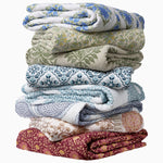 A Quilts & Coverlets hand quilted stack of Lapis Quilt cotton voile blankets, perfect for snuggling up with on a chilly night. - 30497708834862