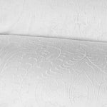 Close-up image of the Amina Ecru Duvet Set by John Robshaw, showcasing a white fabric with an intricate, embossed floral pattern, crafted from the finest quality cotton linen. - 31260962062382