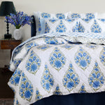 A Mayra Azure Quilt bed with a blue and white floral pattern made of cotton voile fabric. - 30395680915502