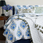 A bed with blue and white bedding, including John Robshaw French Knot Dark Sage Throw pillows. - 30395700641838