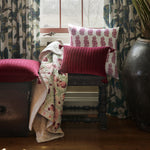 A Tejal Berry Throw by Throws with diamond pattern stitching in front of a window. - 30395699331118