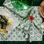 A Bhavin Sage Napkin (Set of 4) from John Robshaw made of cotton, featuring a delightful combination of green and white colors and adorned with an assortment of vibrant fruits. - 30800054878254