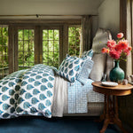 A bedroom with blue and white John Robshaw organic long staple cotton bedding, featuring a 400 thread count Bilva Peacock Organic Duvet and flowers. - 30784071958574