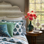 A bed with hand stitched John Robshaw blue and white Bimal Decorative Pillow bedding and a vase of flowers. - 30801409409070