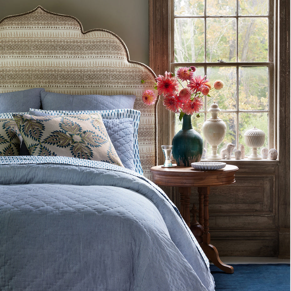 A blue and white bedroom with a John Robshaw Nandi Indigo Quilt headboard.