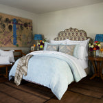 A woven flower motif in the John Robshaw Adesh Mist Duvet Set on a blue bed. - 30784318767150