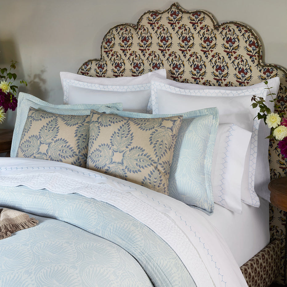 A Verdin Lapis Decorative Pillow by John Robshaw on a bed.