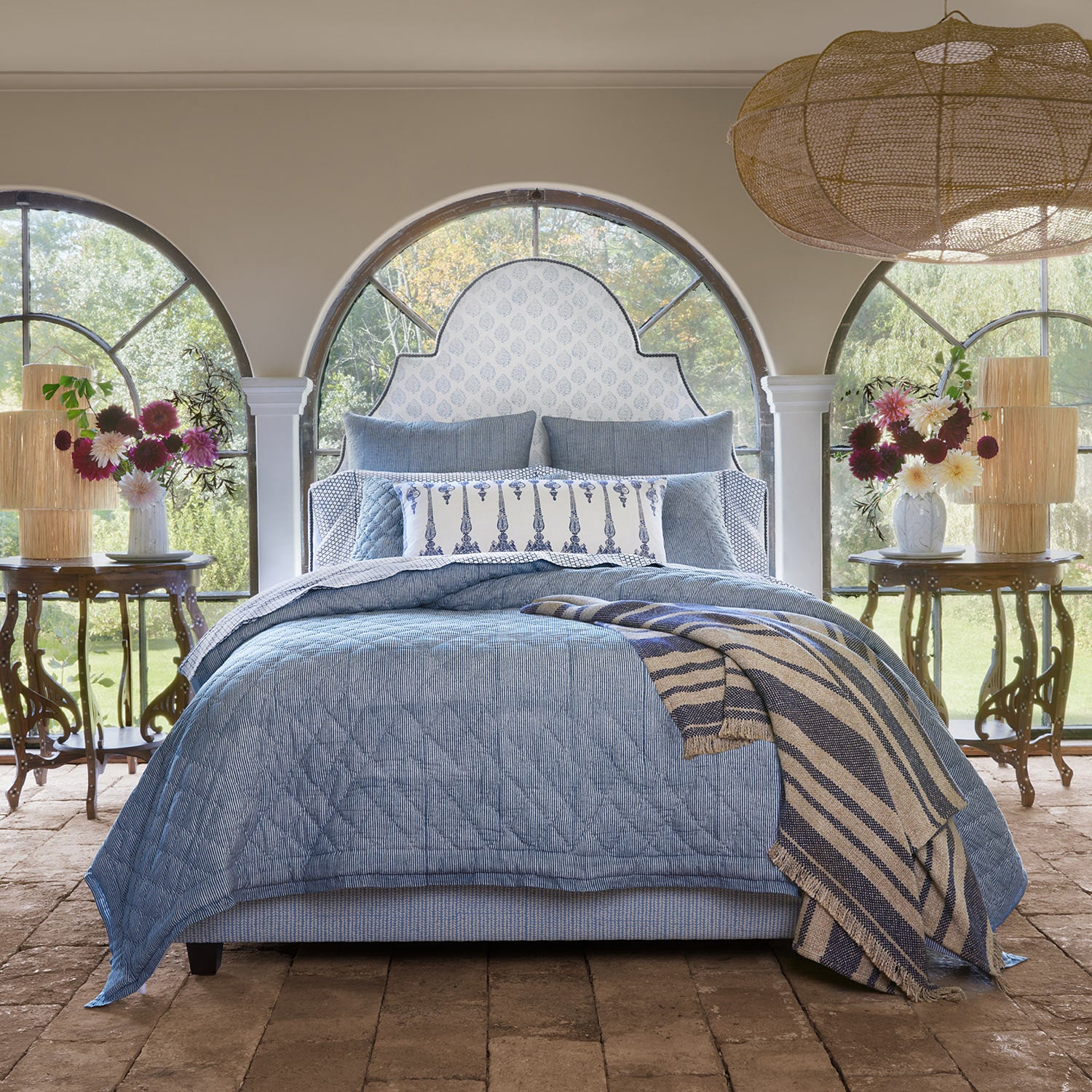 A Nandi Indigo Quilt bed in a bedroom with arched windows, featuring simple stripes. (Brand: John Robshaw)
