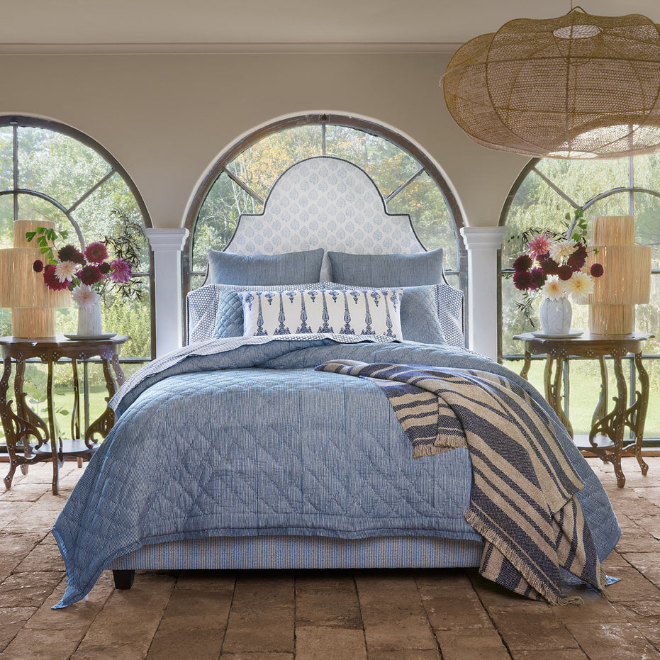A Nandi Indigo Quilt bed in a bedroom with arched windows, featuring simple stripes. (Brand: John Robshaw)