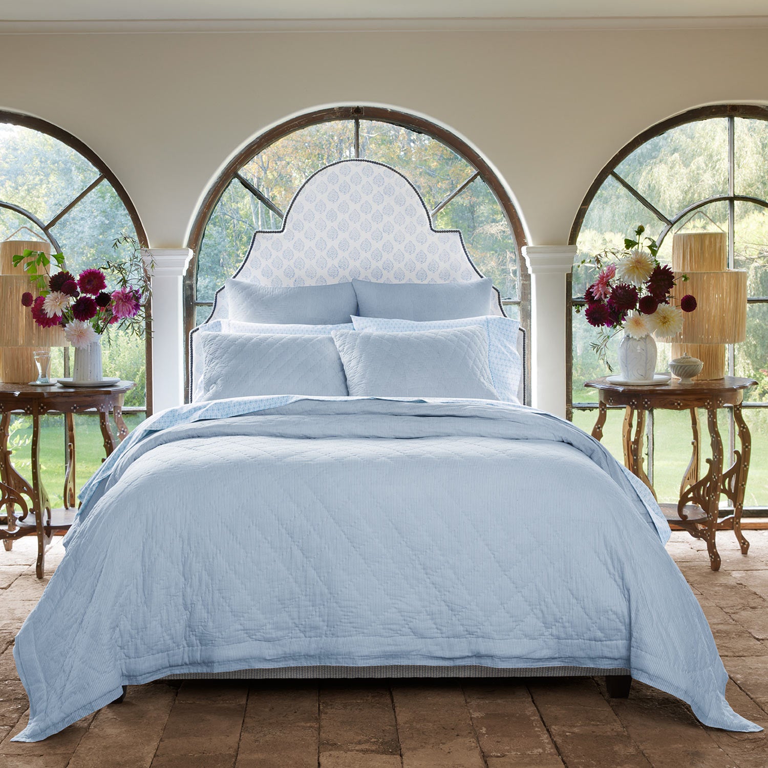A cotton voile bed with a Nandi Light Indigo Quilt by John Robshaw and arched windows.