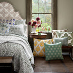 A hand block printed Verdin Dark Sage Decorative Pillow by John Robshaw on a bed in a room with a window. - 30801458495534