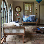 A living room with a John Robshaw Fulki Decorative Pillow hand block printed indigo edging on a brick floor. - 30801465507886