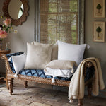 A blue and white cushioned bench in front of a window with John Robshaw's Woven Ivory Kidney Pillow. - 30801465901102