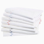 A stack of Stitched Indigo Organic Sheets from Sheets & Cases accented with blue and red embroidery. - 30446587641902