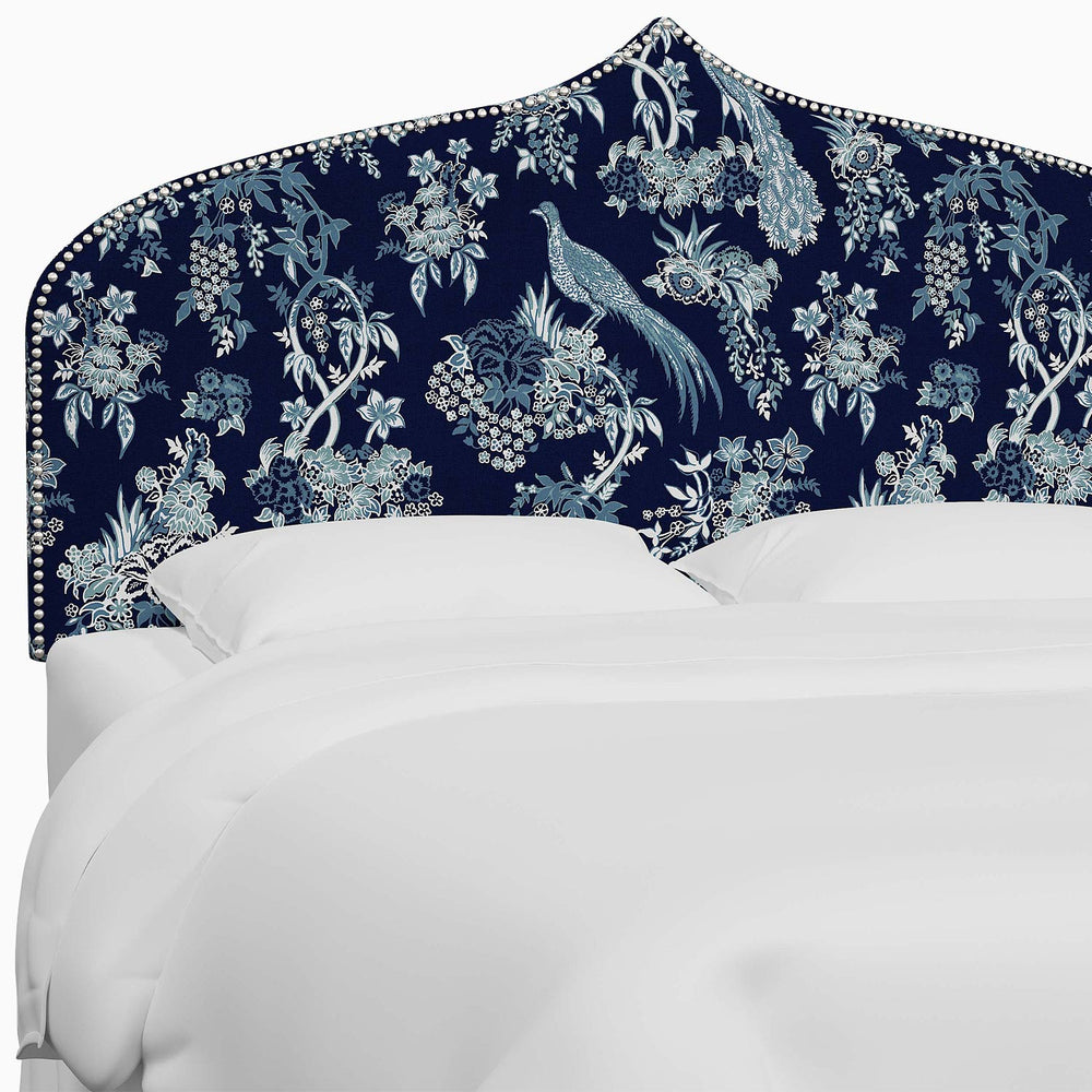 A bed with a blue and white John Robshaw Alina Headboard featuring floral prints inspired by Mughal arches.