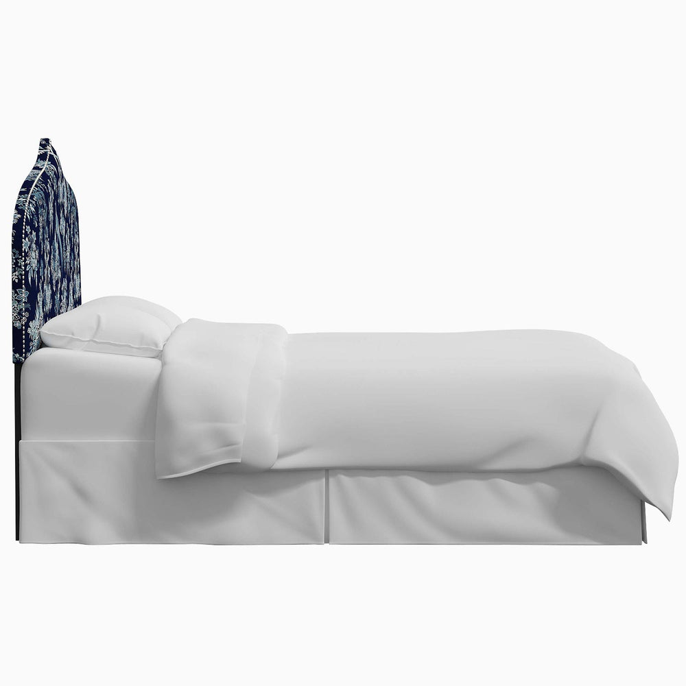 A bed with a blue Alina Headboard and John Robshaw Mughal arches print on the white covers.