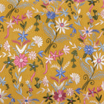 A close-up of embroidered floral patterns in a range of colors, including pink, white, blue, and green, on the mustard yellow cotton linen background of the John Robshaw Kia Marigold Kidney Pillow. - 31259675033646