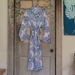 A Daru Robe by John Robshaw, a blue and white cotton voile robe with pockets, hanging on a door, perfect for relaxing. - 30822536544302