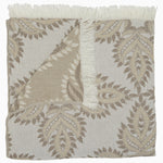 The Dasati Sand Throw by John Robshaw is a beige and white patterned blanket made from stonewashed cotton, featuring fringed edging and partially folded to reveal the woven design on the reverse side. - 31272470839342