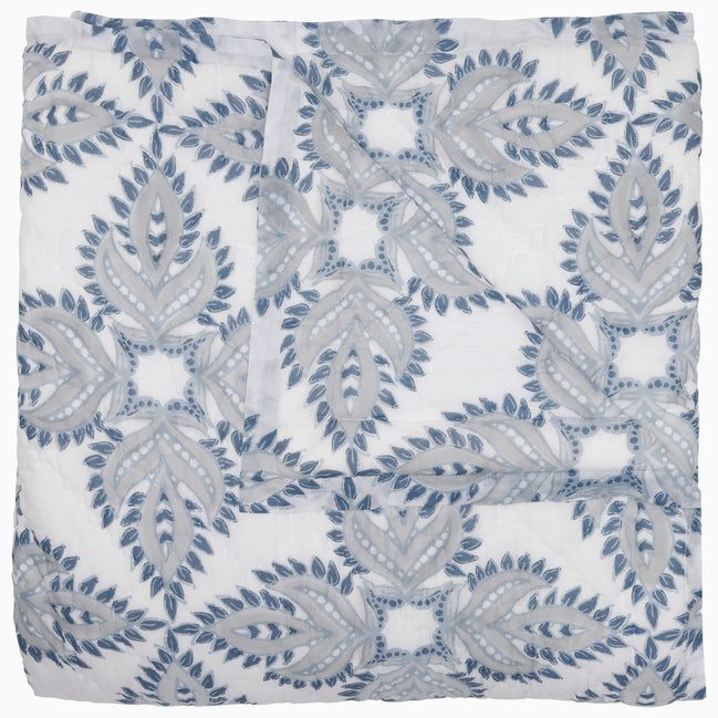 Folded John Robshaw's Dasati Lapis Quilt, featuring a blue and gray geometric leaf pattern on a white background, crafted from cotton voile.
