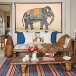 A vintage-inspired living room with a colorful rug and a John Robshaw Grey Elephant on Blush Tapestry, hinting at hand-painted aesthetics and a hint of traveling in India. - 30720448757806
