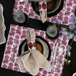 A dining table set for two features striped napkins adorned with Nand Berry Beaded Napkin Rings from Tabletop, complemented by floral print placemats, utensils, and glassware. Decorative flowers accent the upper right corner. Made in India.

 - 31307862212654