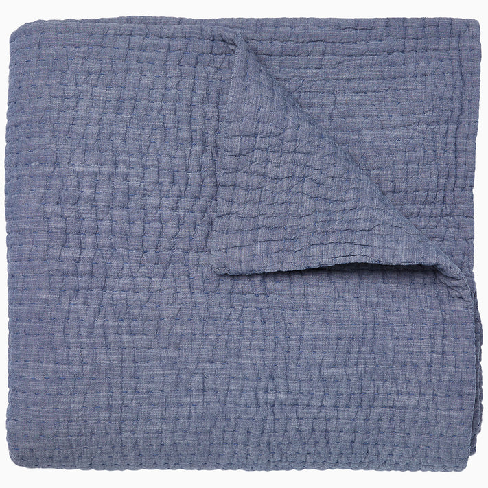 A Vivada Indigo Woven Quilt by John Robshaw folded on top of itself.