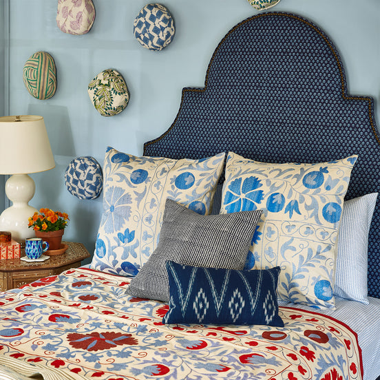 A John Robshaw Custom Dara Bed in a room with a blue wall, available for white glove delivery.