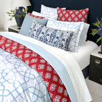 A bed with Stitched Light Indigo Organic Sheets by John Robshaw in red, blue, and white, featuring embroidered designs. - 30270343872558