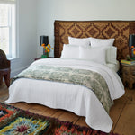 A white bed in a bedroom with a Quilts & Coverlets cotton chambray Asma Woven Quilt and a colorful rug. - 29299581419566