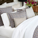 A John Robshaw Stitched Sand Organic Sheets bed with a blue and white comforter featuring embroidered designs, accompanied by matching pillows. - 29299684048942