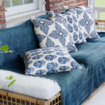 A blue and white wicker couch on a porch adorned with small Adira Indigo Outdoor Decorative Pillows by John Robshaw. - 29302598041646