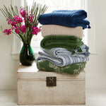A stack of Velvet Moss Throws stacked on top of a chest. - 29302498295854