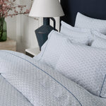 A bed with Ramra Indigo Organic Sheets made of organic cotton percale and a lamp. - 29299679264814
