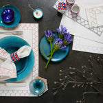 A table setting with machine washable John Robshaw blue and white cotton slub plates and napkins, hand stitched with Stitched Light Indigo Placemats. - 29333345632302