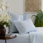 A bed with Kama Light Indigo Organic Sheet Set from Sheets & Cases and a vase of flowers. - 28202297983022