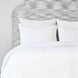 A cotton voile bed cover with a blue and white polka dot duvet cover, featuring the Organic Hand Stitched Light Indigo Quilt by John Robshaw.