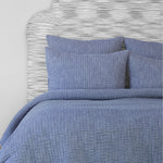 A super fine Vivada Indigo Woven Quilt made with cotton chambray, adorned with a blue quilt and pillows hand stitched by Quilts & Coverlets. - 28271561572398